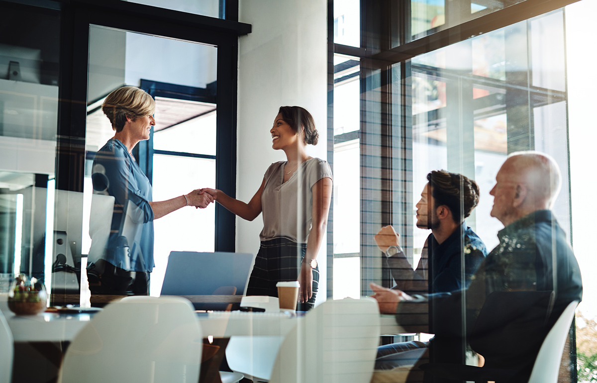 A new executive is introduced to senior management in a conference room.